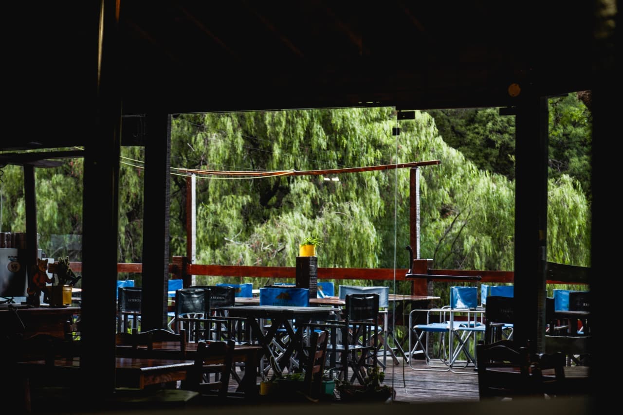 Terraza del restaurante del complejo Cerro Uritorco rodeada de monte